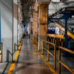 Interior pabrik modern dengan mesin industri dan sistem conveyor sebagai contoh faktor produksi tetap